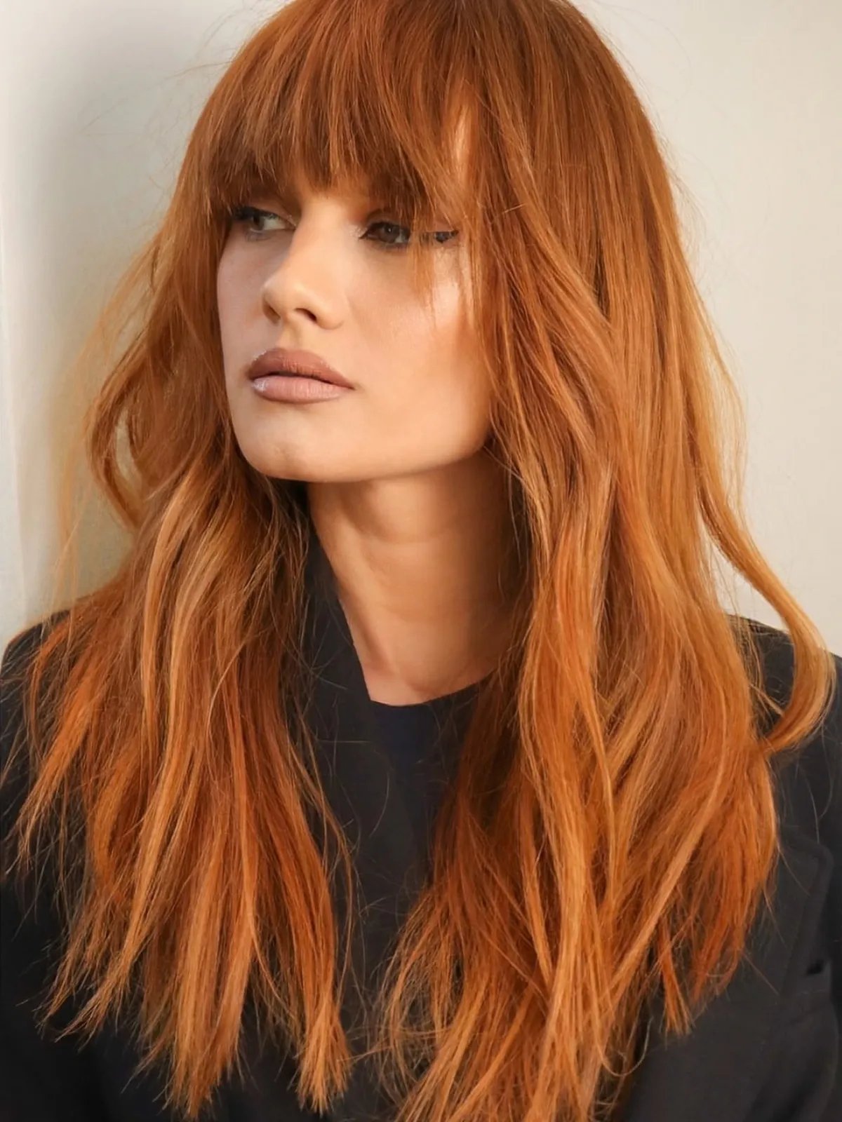 Model with long, ginger hair featuring bangs.