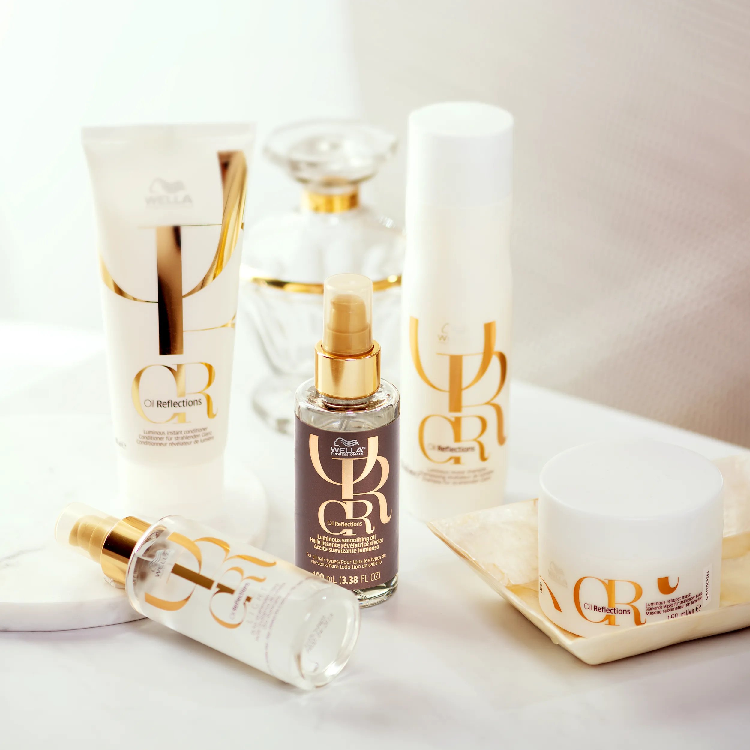 Packshot of all Wella Professionals Oil Reflections products. This includes Reveal Shampoo, Instant Conditioner, Smoothing Oil and Reflective Oil.