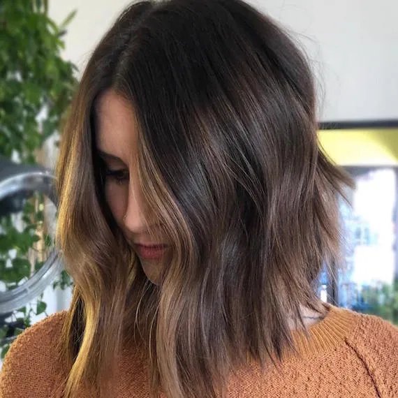 Photo of woman with brunette balayage lob styled in loose waves, created using Wella Professionals.