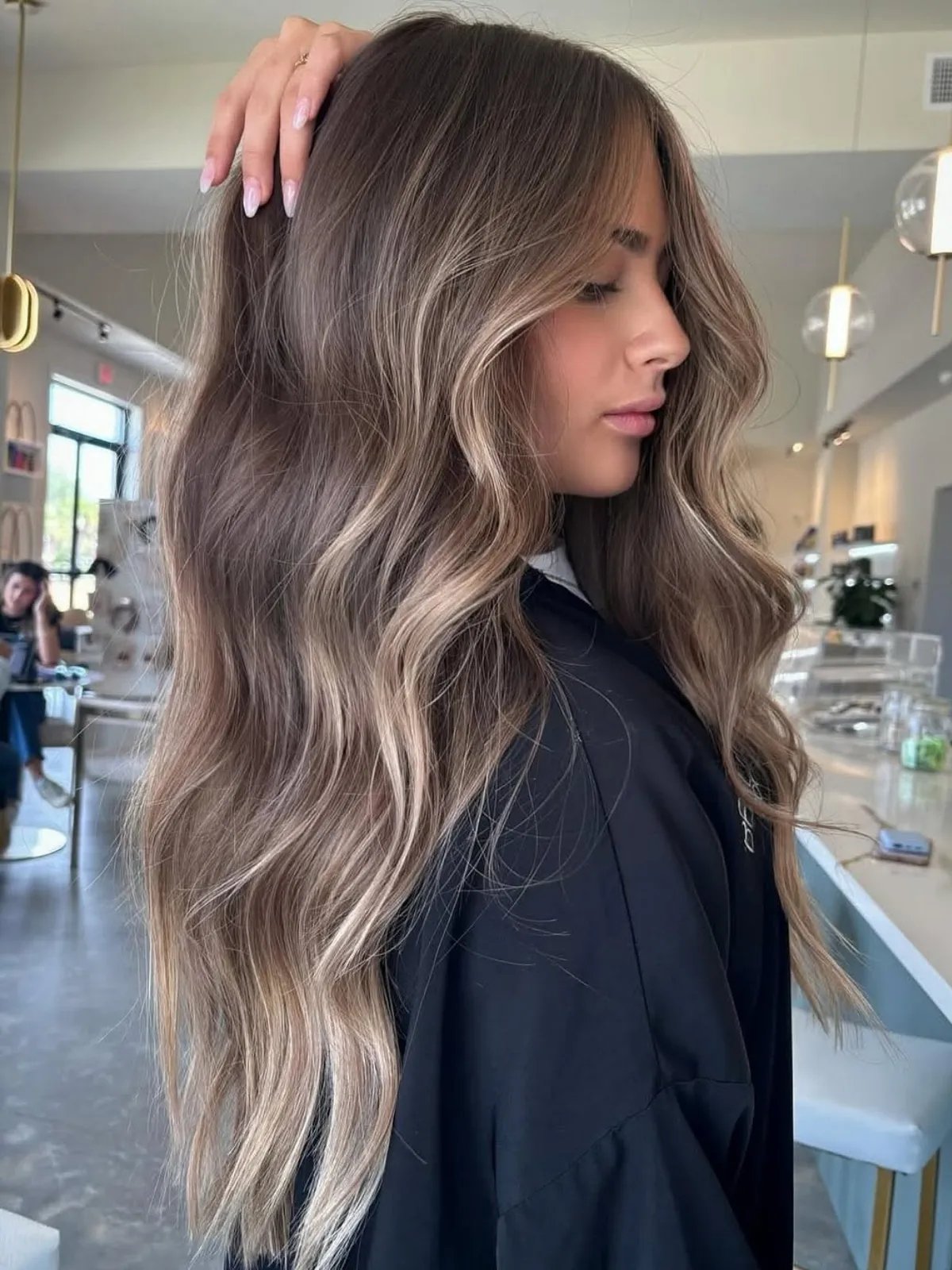Model with dark blonde, wavy hair featuring a subtle beige blonde balayage.
