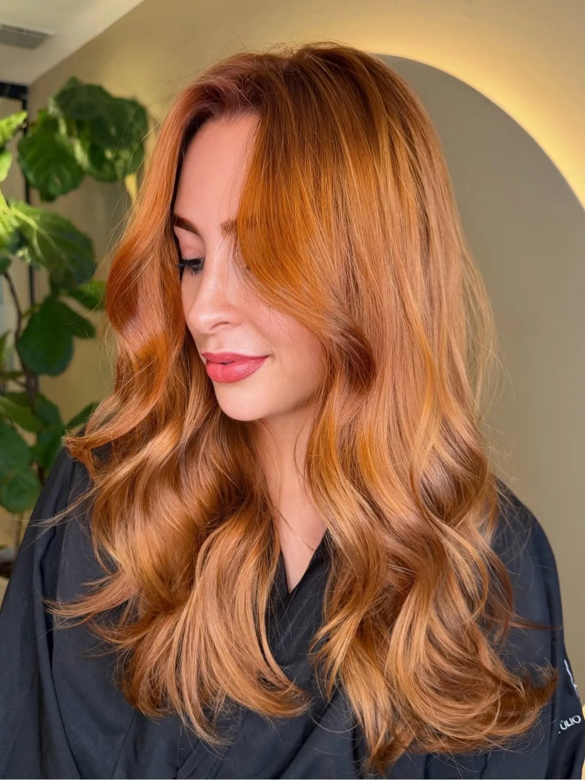 Model with long, loosely curled, copper hair with a honey blonde glow.