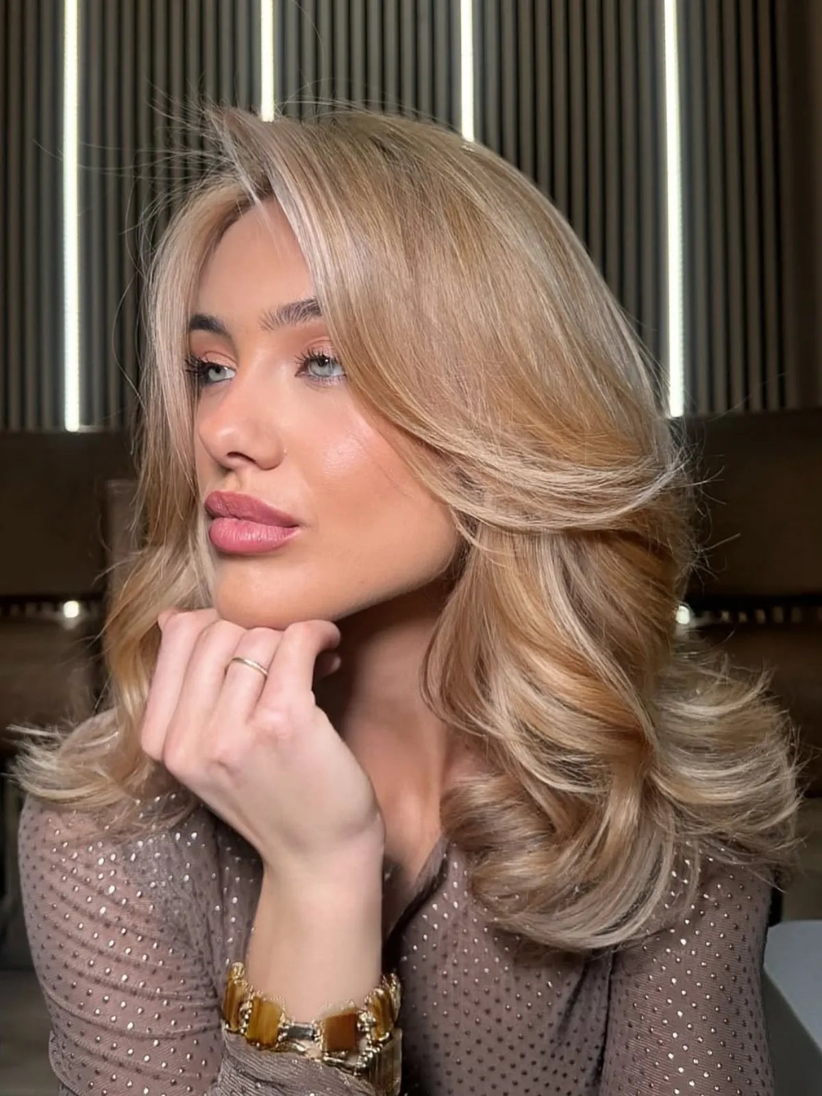 Model with golden champagne hair styled in a bouncy blow-dry.