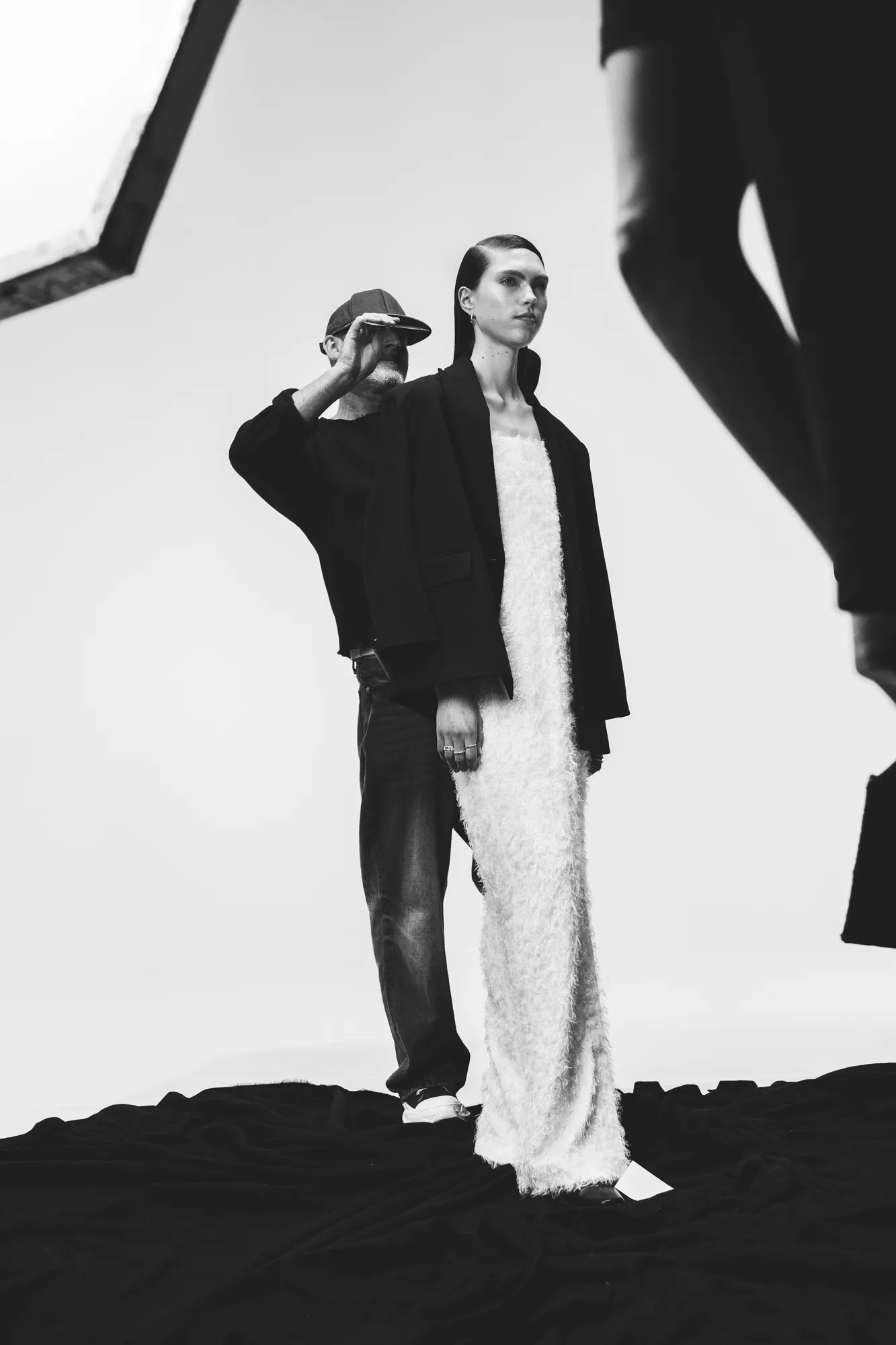 Black and white image of male hairstylist combing through a model's brunette hair. 