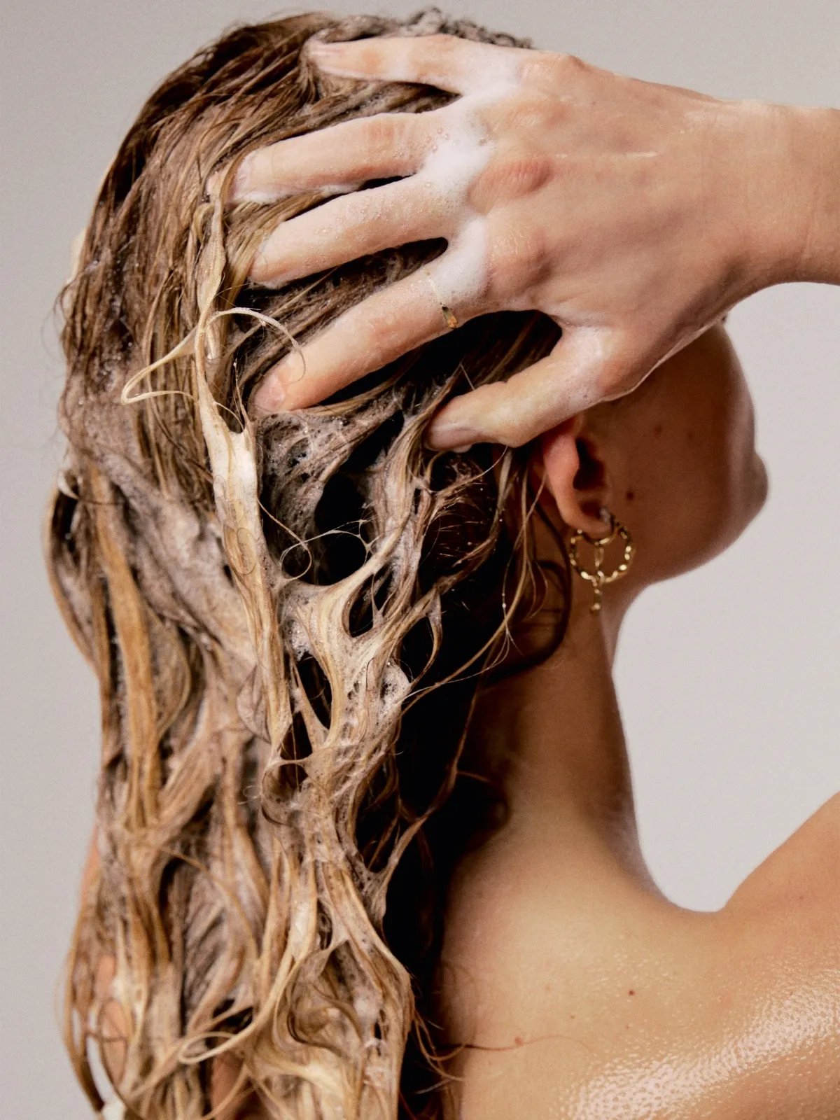 Model massages shampoo into wet, blonde hair.