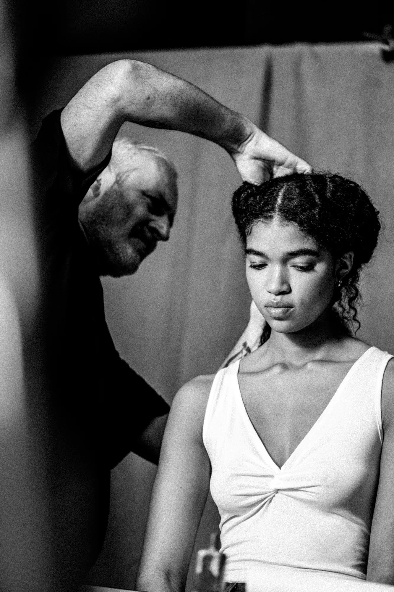 Black and white image of model seated and hairstylist stood and adjusting their hair