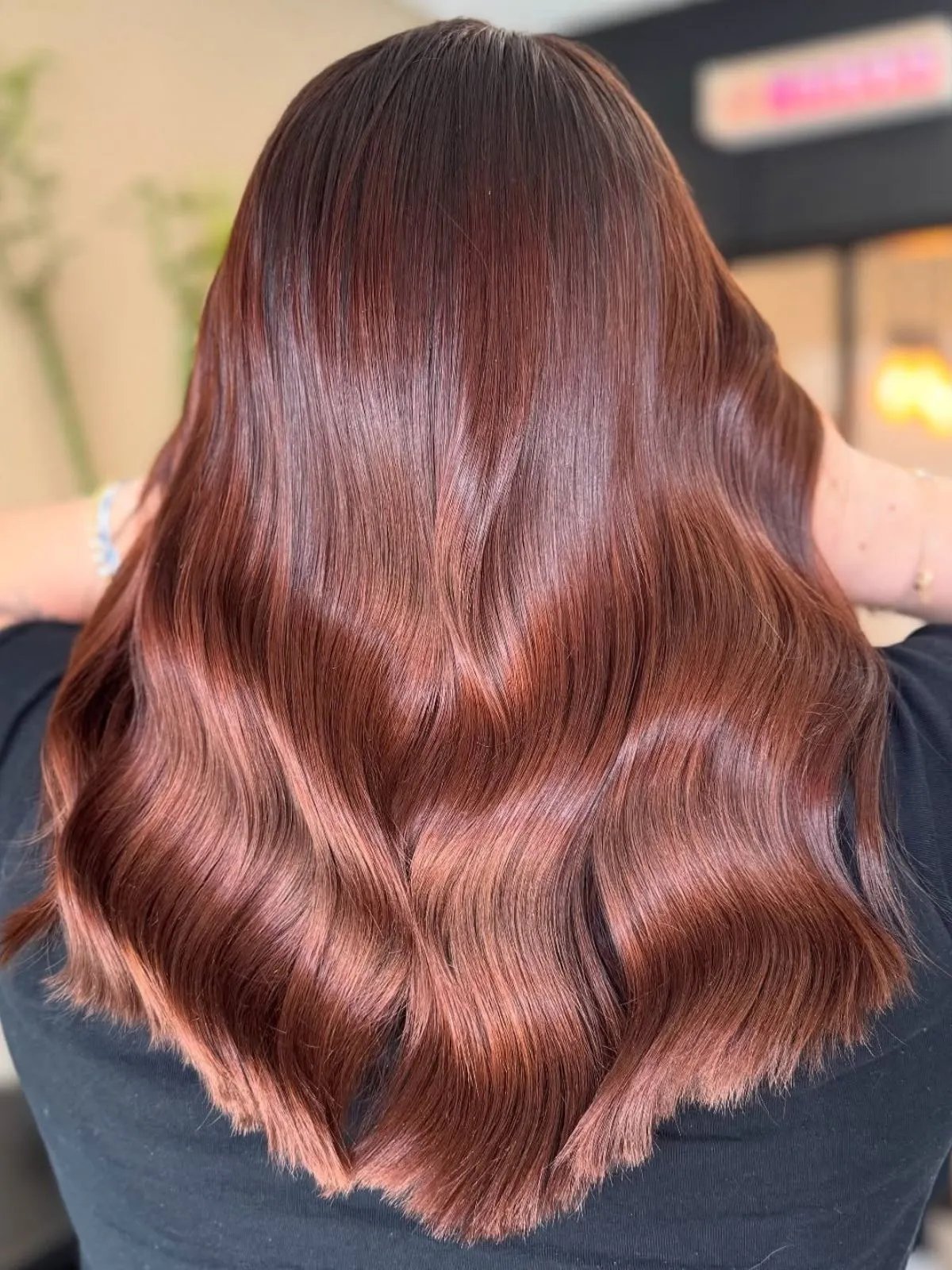 Model with loosely waved, auburn hair featuring rose tones through mid-lengths and ends.