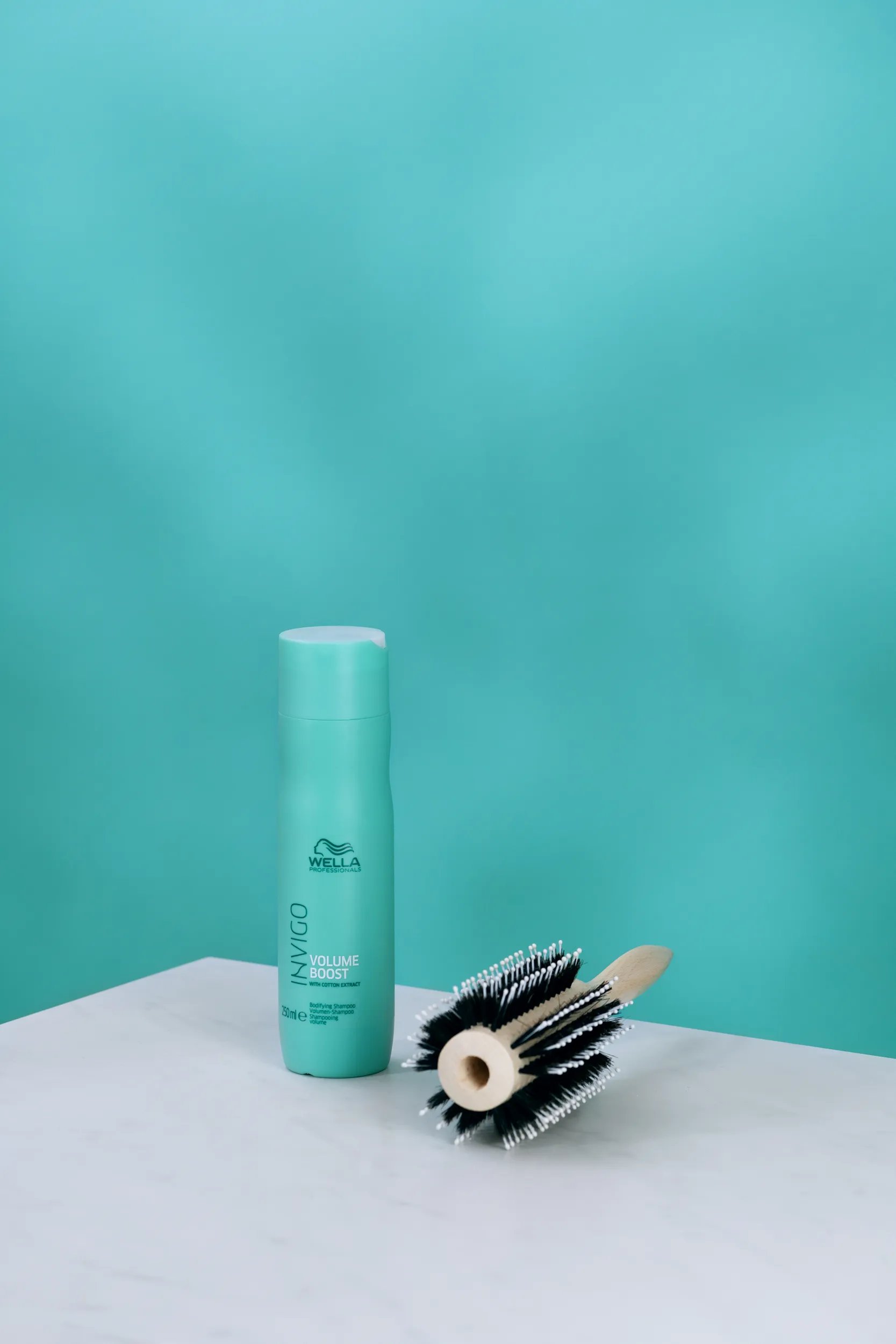 INVIGO Volume Boost Bodifying Shampoo next to a large round brush.