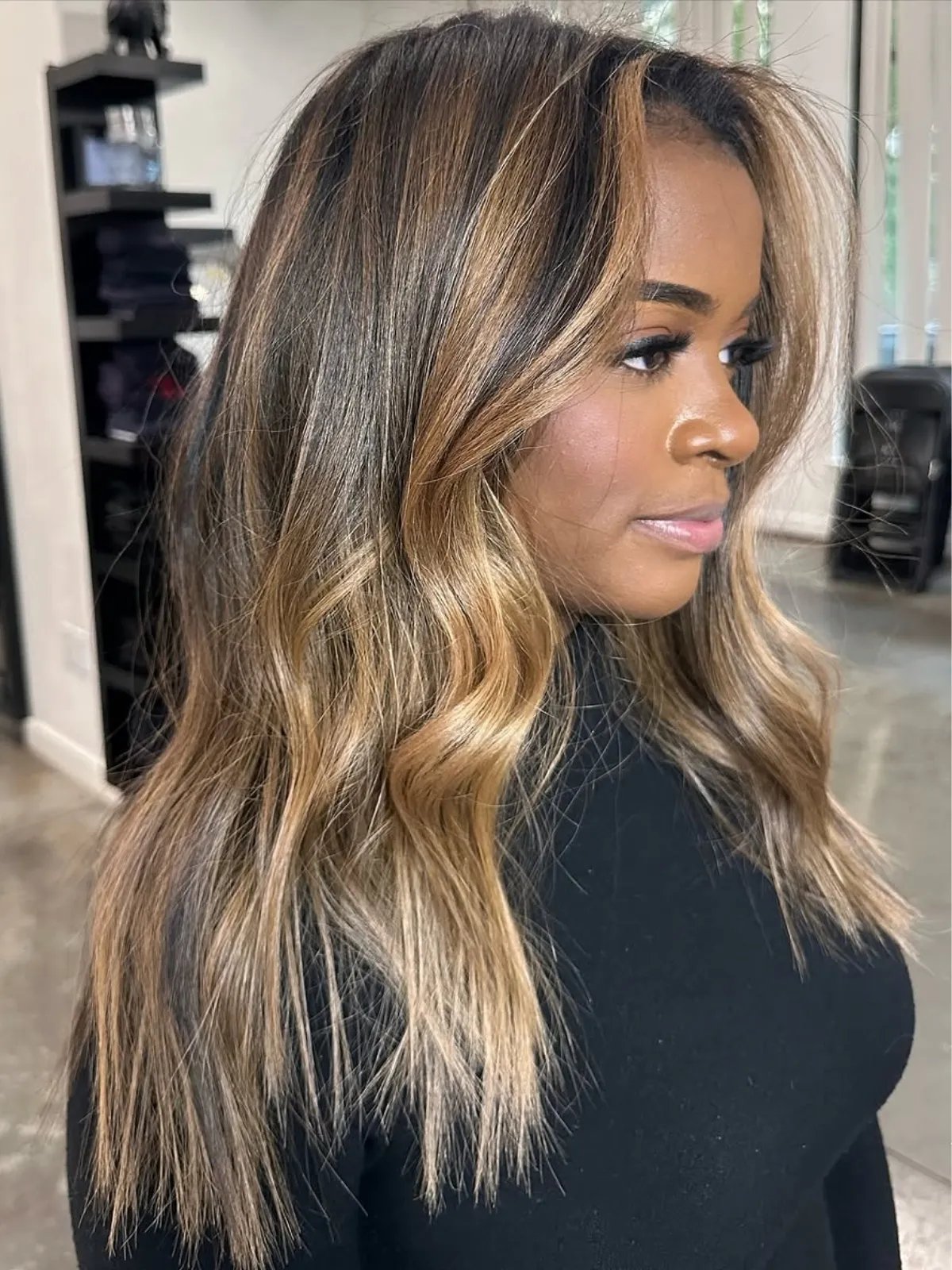 Model with dark brown hair featuring caramel blonde highlights.