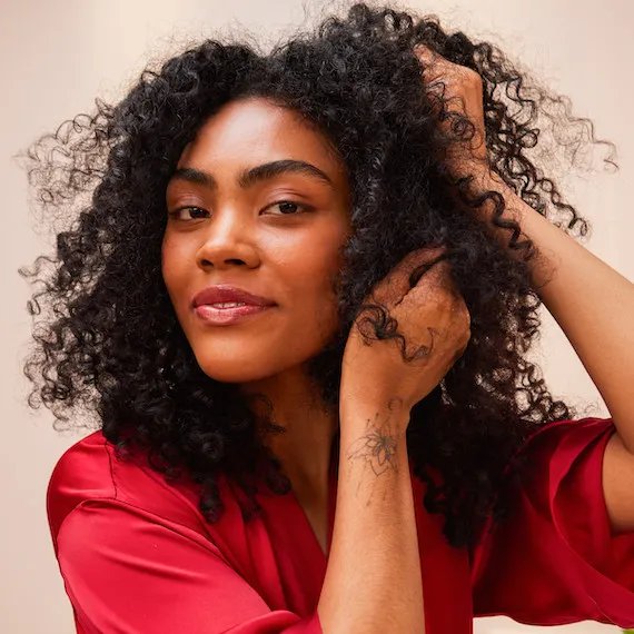 Model with long, dark, curly hair applies ULTIMATE REPAIR Night Serum.