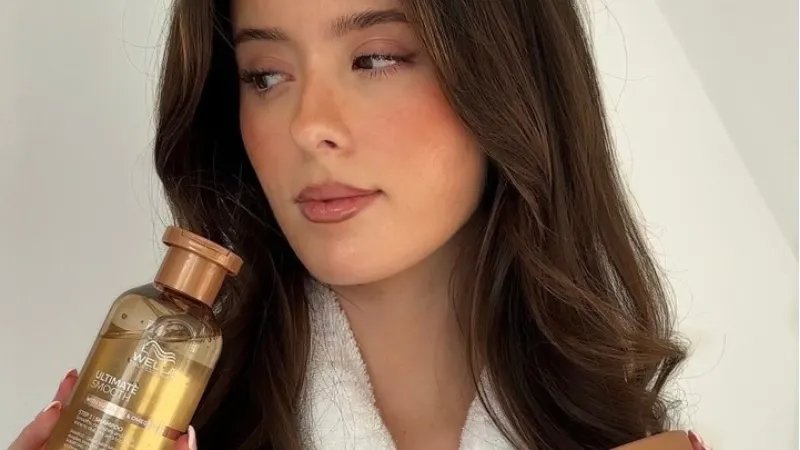 Model with long, brown hair holding ULTIMATE SMOOTH Shampoo and ULTIMATE SMOOTH Mask.