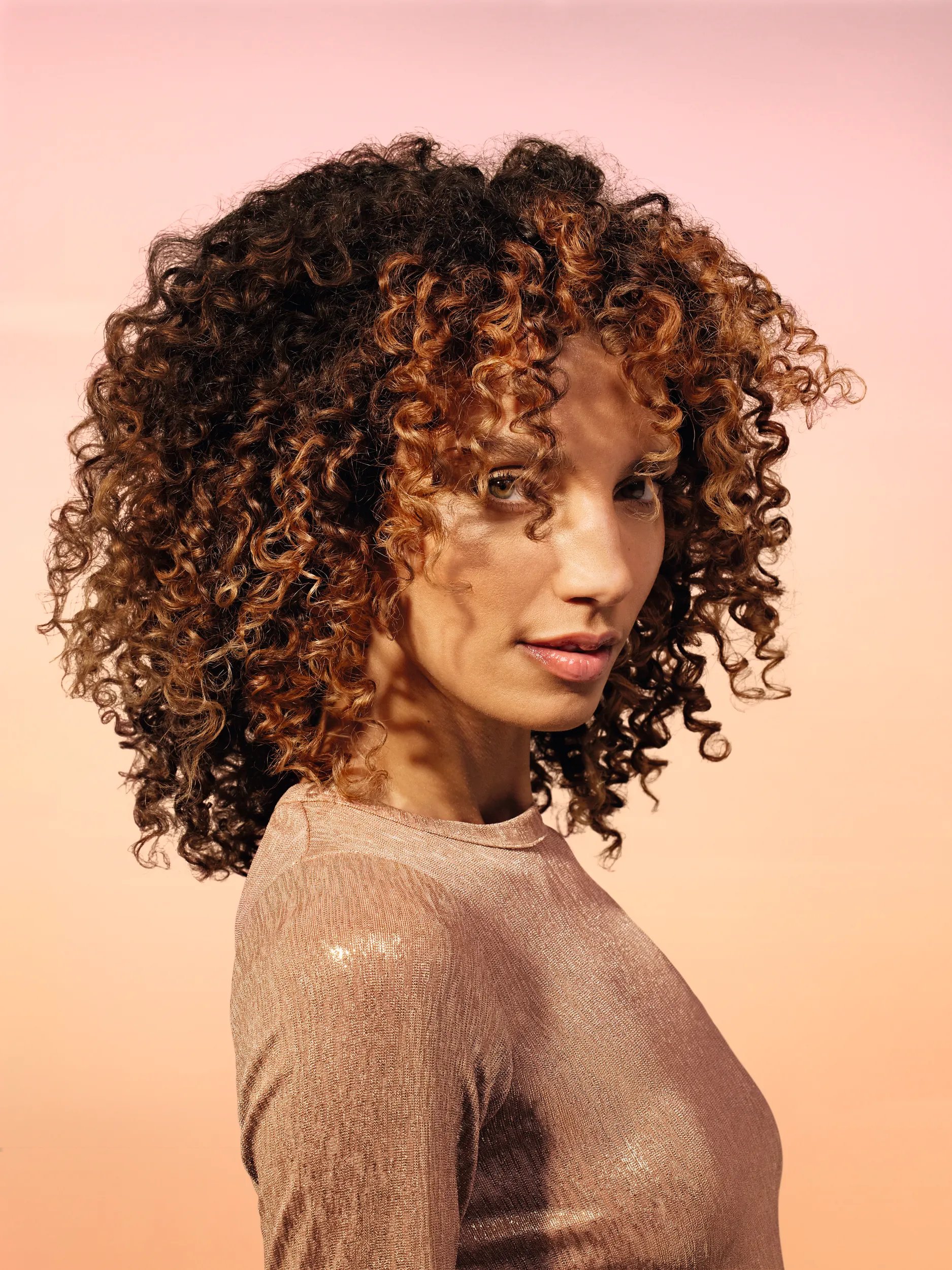 Model with curly brown hair looking at the camera