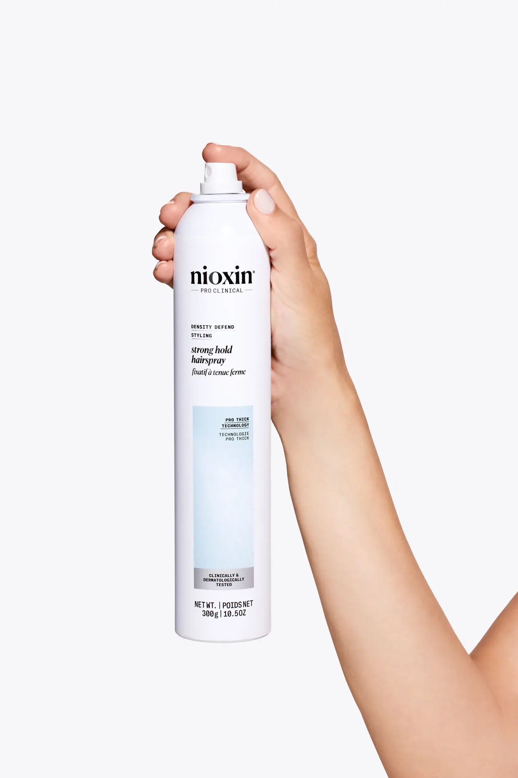 Nioxin Strong Hold Hairspray in mano su sfondo bianco