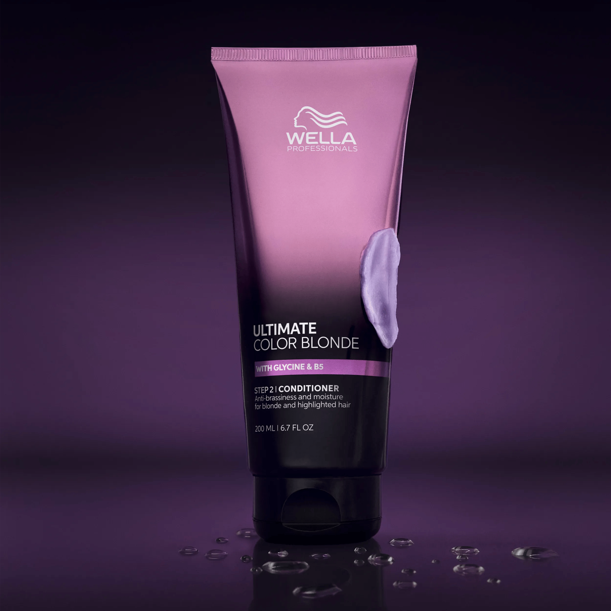 Product image of ULTIMATE COLOR Blonde Conditioner against a gradient purple background. Product has water droplets scattered on the surface below and a smear of the purple conditioner on the side of the tube.