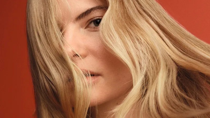 Model with blonde, wavy hair falling over eyes. 