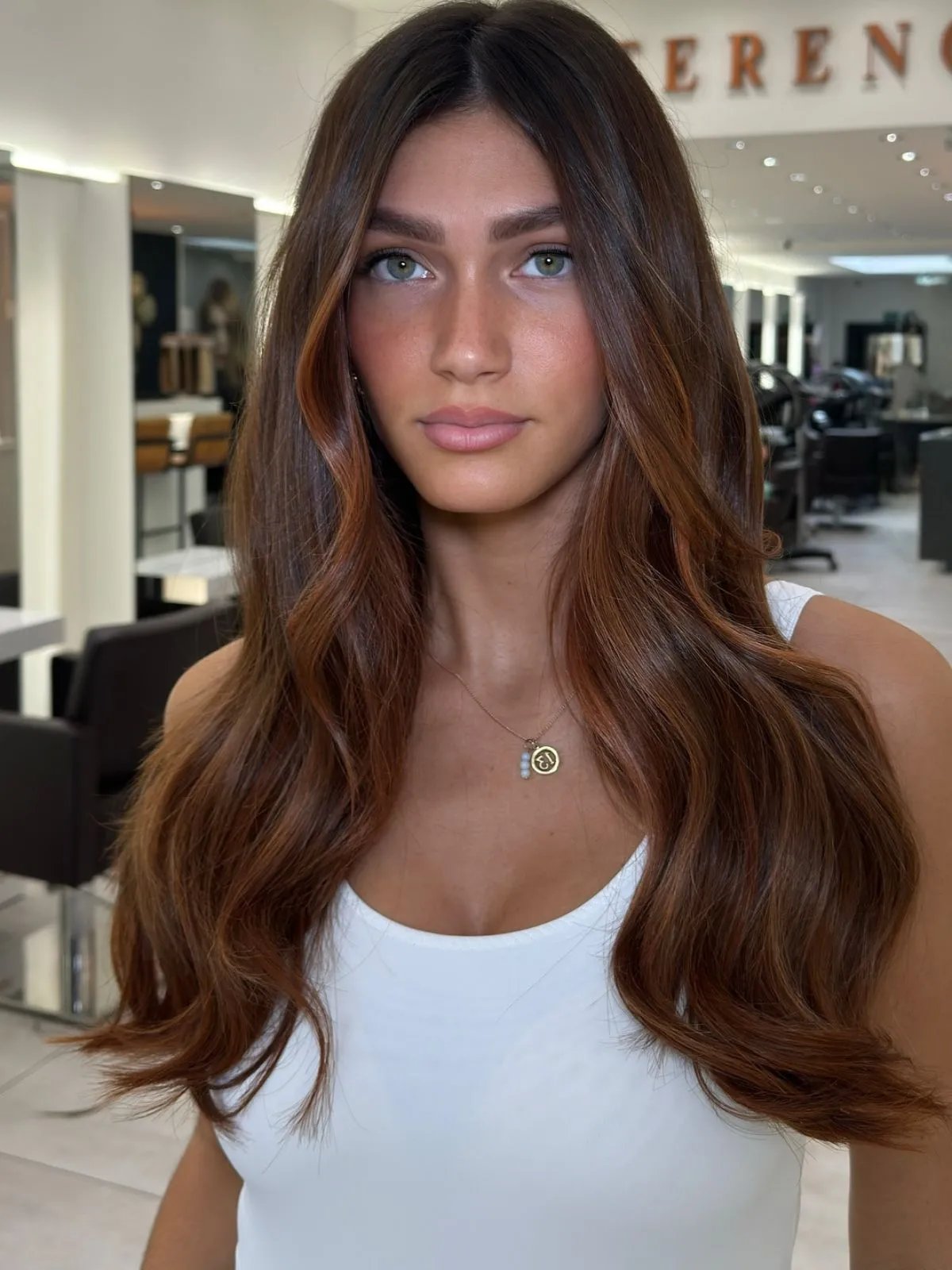 Model with silky brown hair featuring auburn highlights.