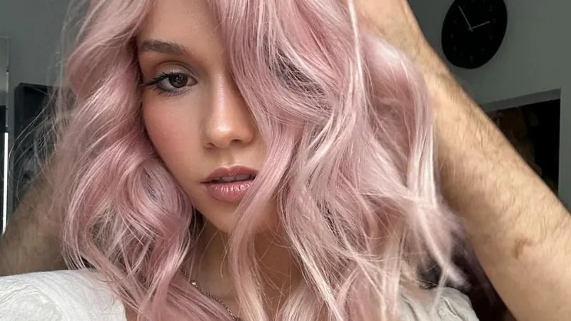 Model with loosely curled, platinum pink hair. 