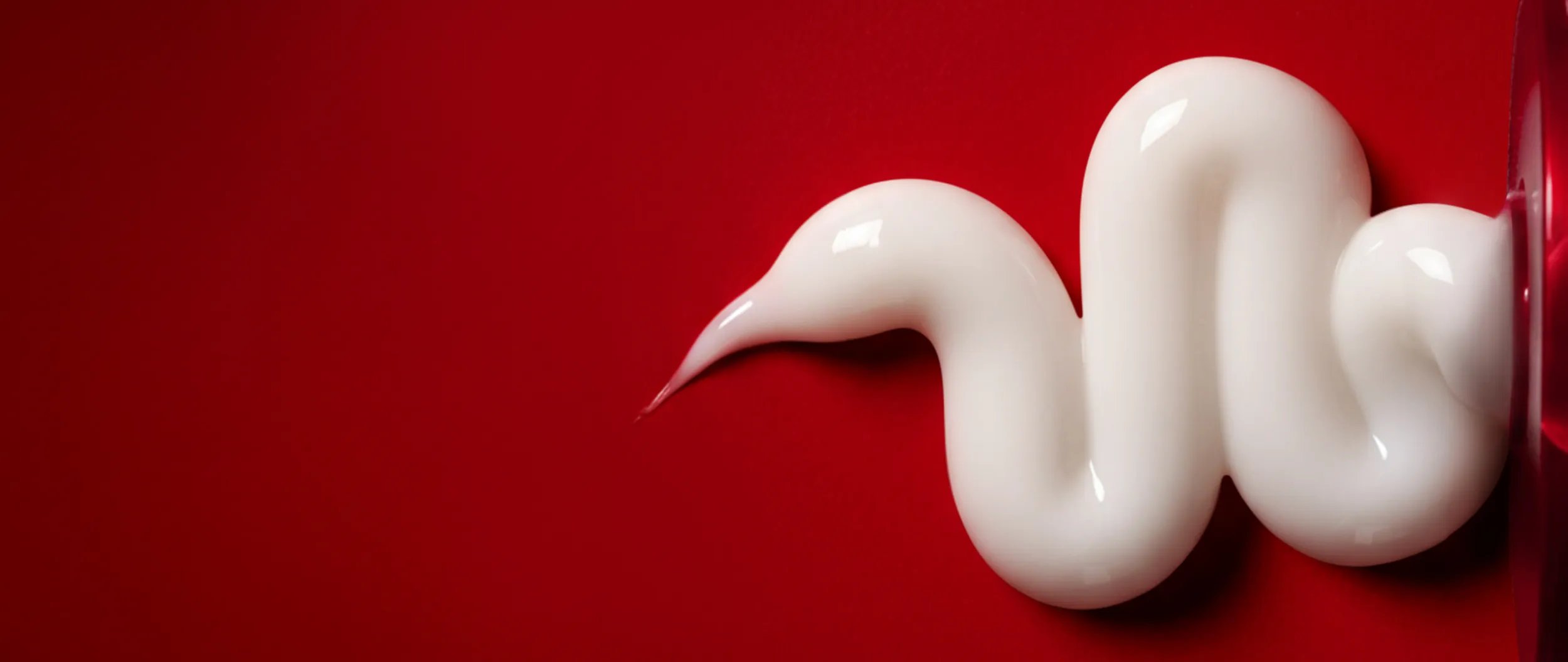 Cream squeezed onto a red background.