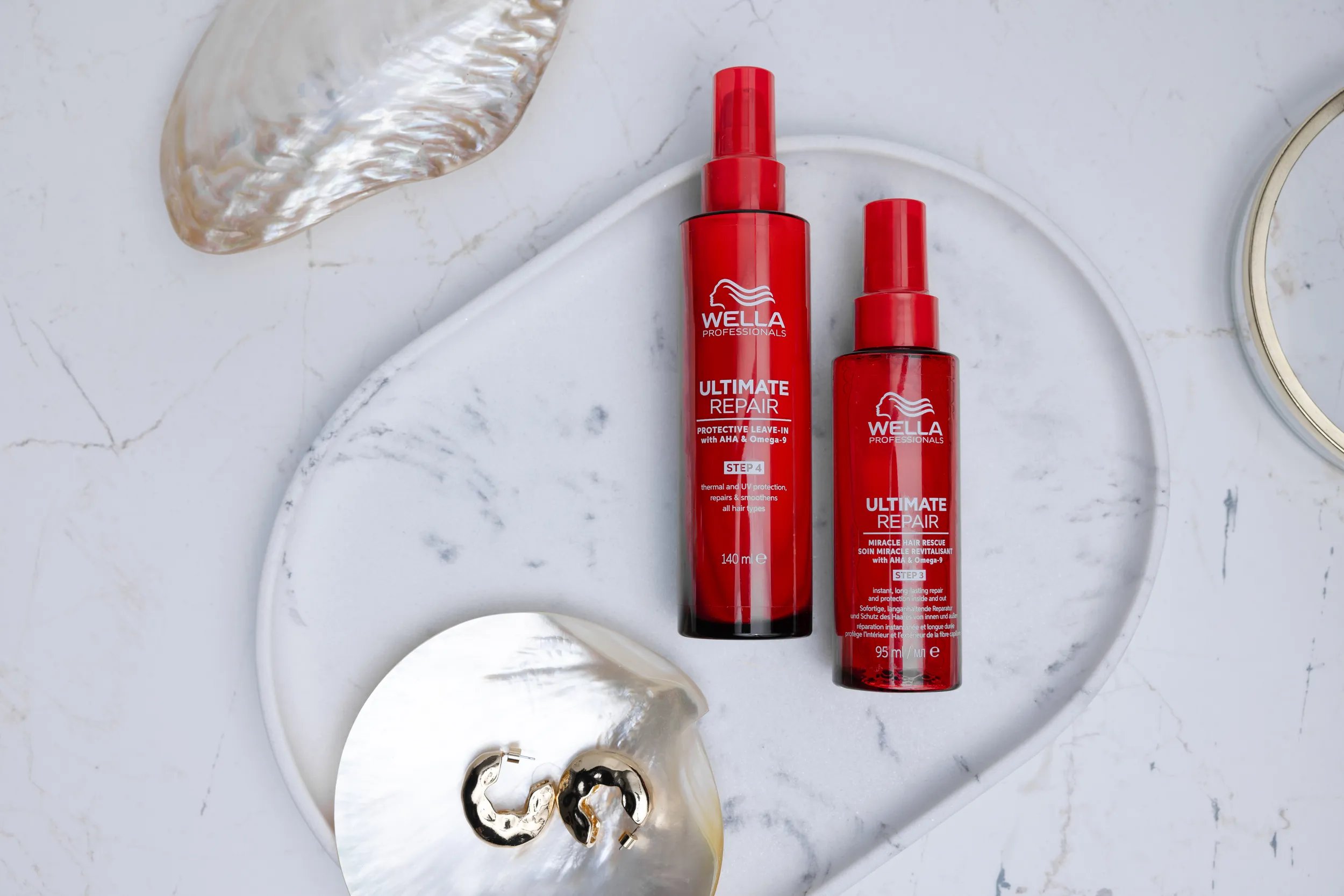 "ULTIMATE REPAIR Protective Leave-In et Miracle Hair Rescue sur un support en plastique.
surface en marbre."