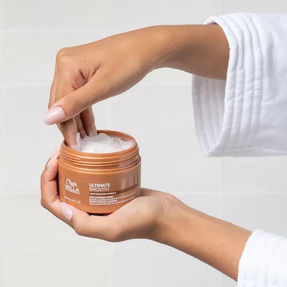 Model scoops ULTIMATE SMOOTH Mask out of the jar.