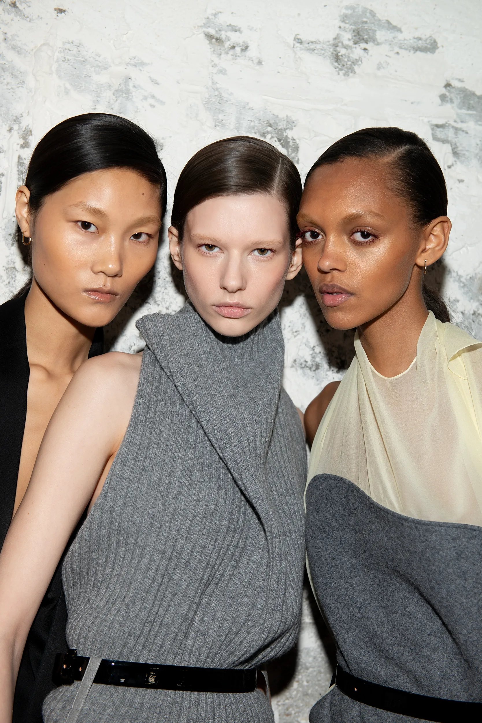 Three models face the camera backstage at Victoria Beckham’s Paris Fashion Week show.