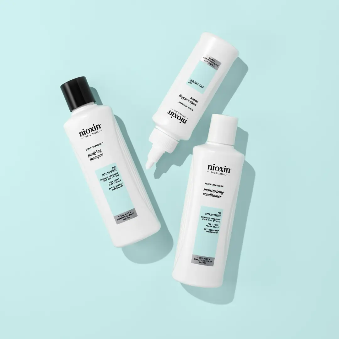 nioxin shampoo, conditioner and scalp soothing serum bottles against baby blue background