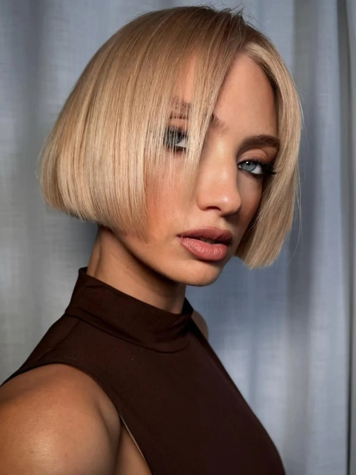 Model with sleek, straight, butter blonde bob haircut.