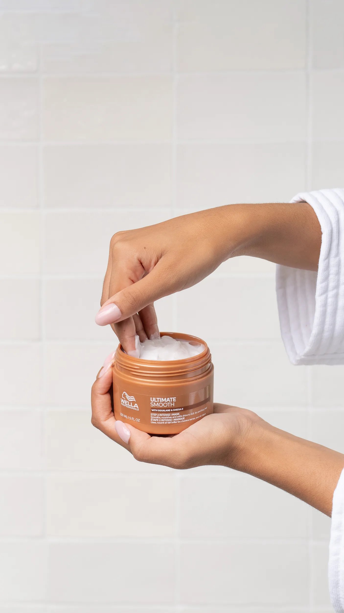 Model reaches into a tub of ULTIMATE SMOOTH Mask.