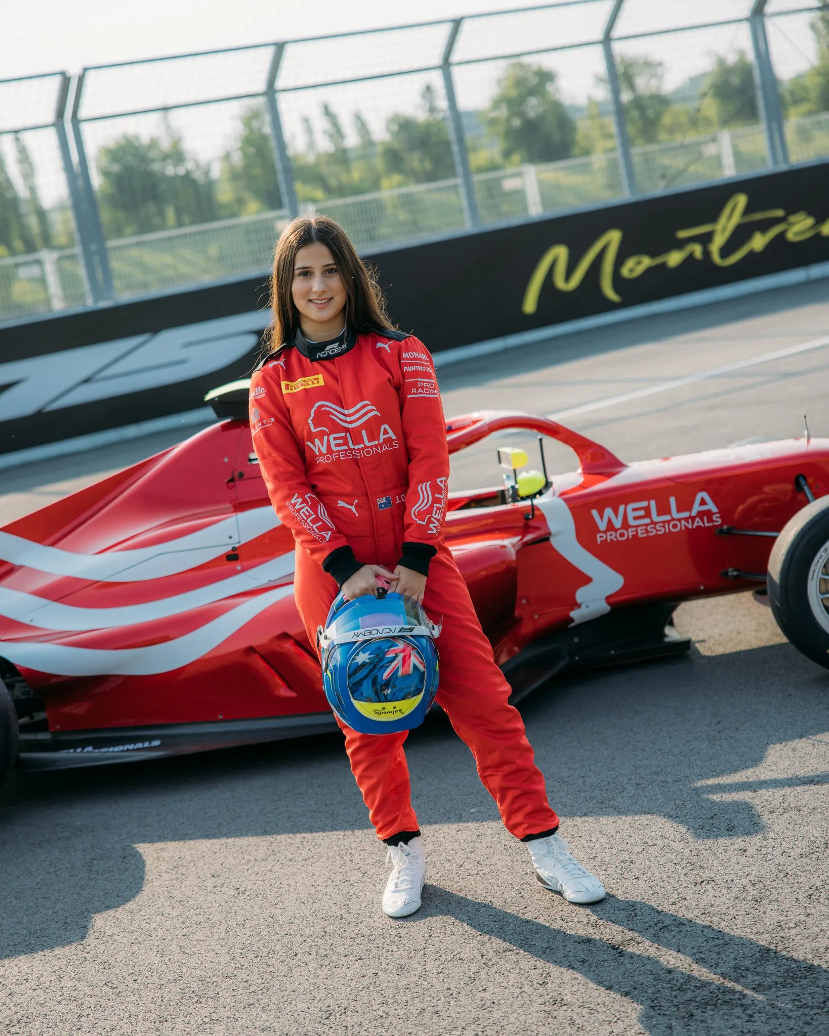 Joanne Ciconte from F1 Academy wearing a red Wella Professionals suit and car