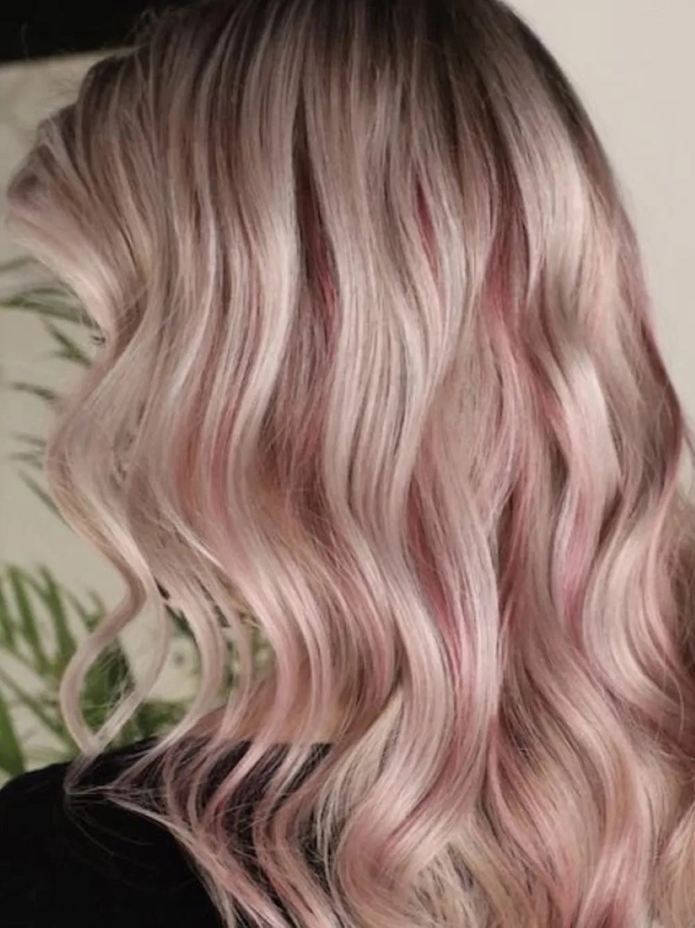 Side view of wavy hair in a rose blonde shade with soft pink tones.