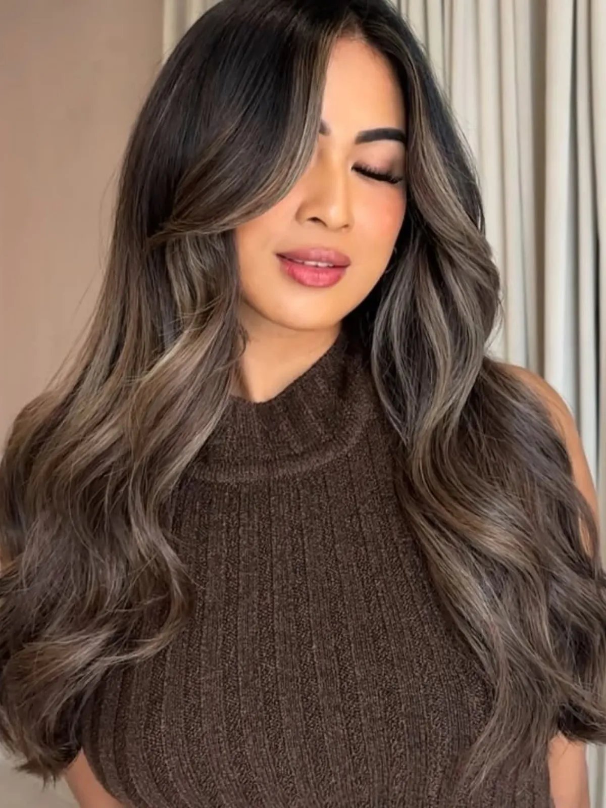 Model with dark brown hair featuring a subtle ash blonde balayage through the face frame.