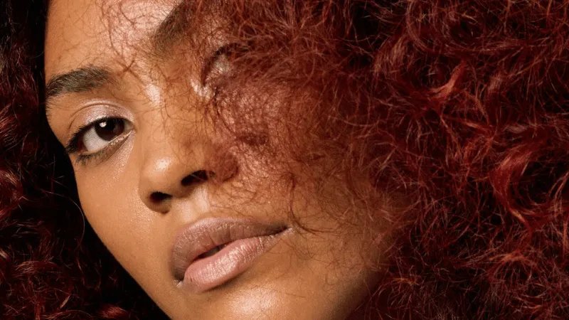 Close-up of model with cherry chocolate, curly hair.