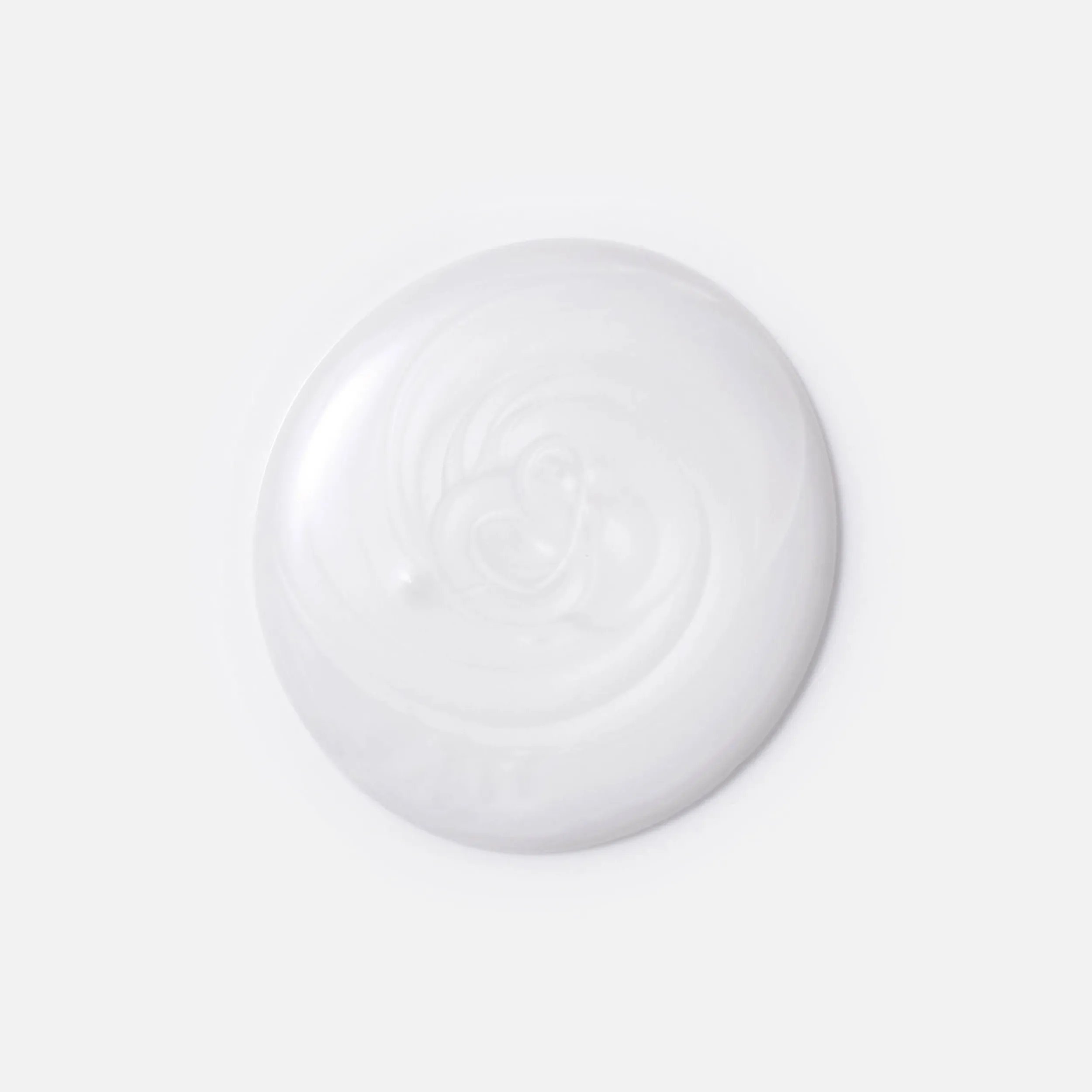 Photographie en gros plan d'une goutte circulaire de shampoing INVIGO Brilliance pour cheveux rêches sur fond blanc, avec un texte indiquant "bouclier antioxydant, aide à contrôler le processus d'oxydation après la coloration" et "purificateur de métaux, protège des métaux nocifs présents dans l'eau".