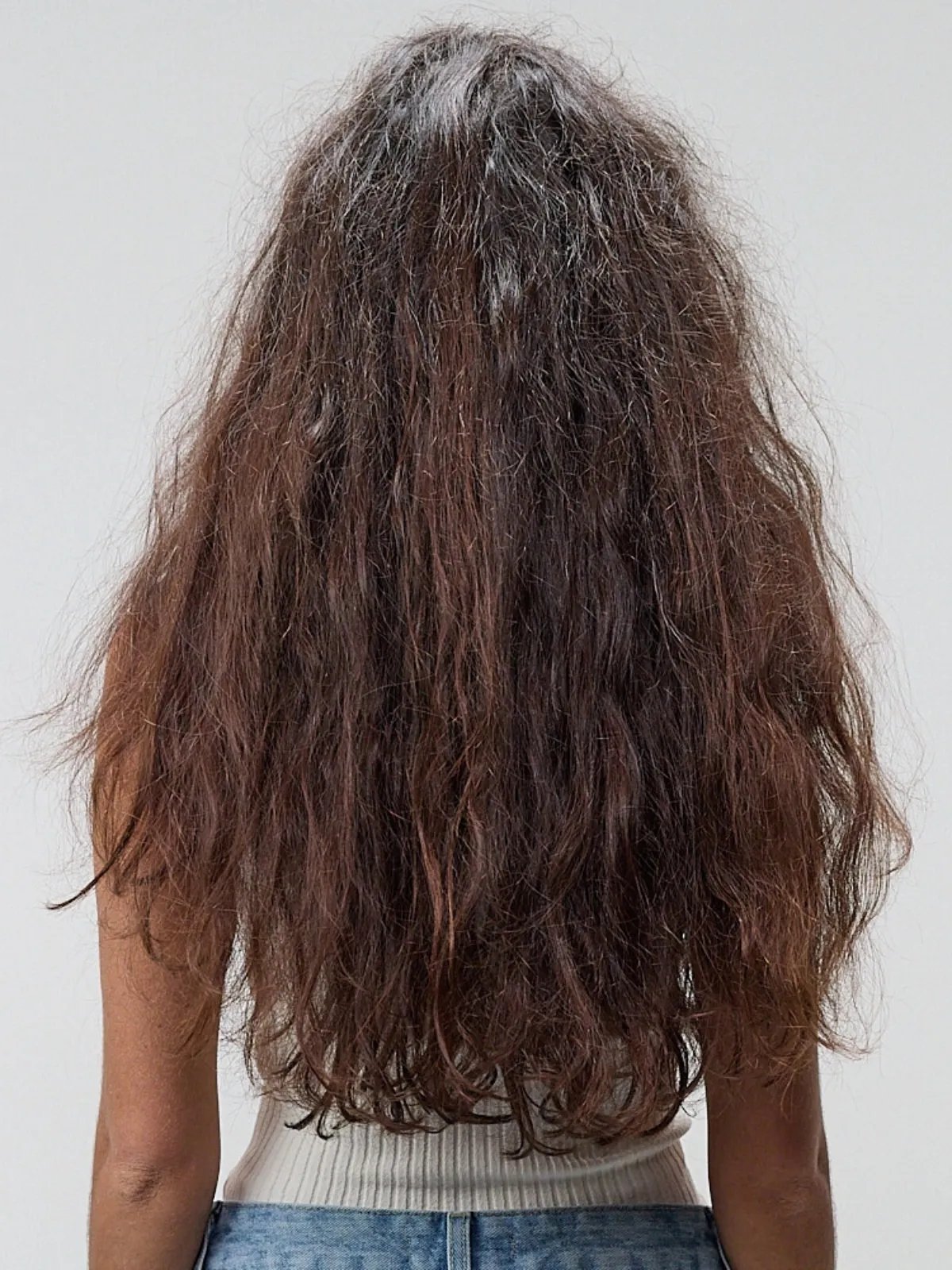Model’s long, dark brown hair appears frizzy before a SmoothFiller™ service.