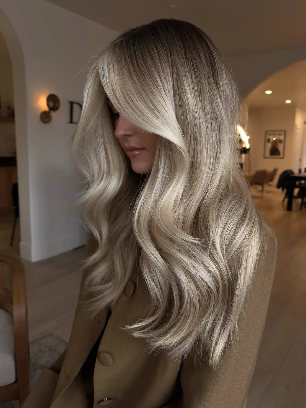 Model with long, glossy, champagne blonde hair with a soft root shadow.