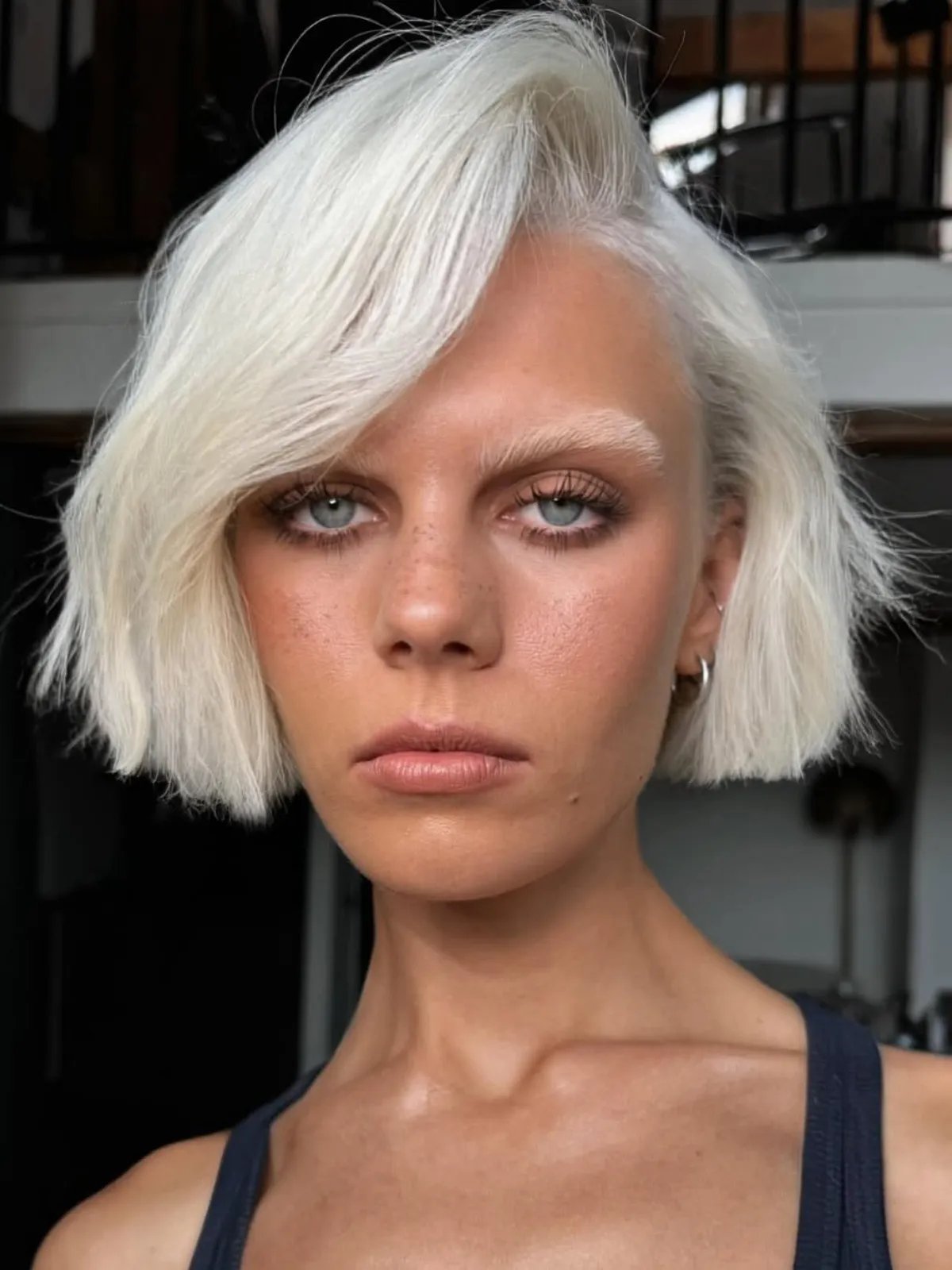 Model with white blonde micro bob swept to one side.