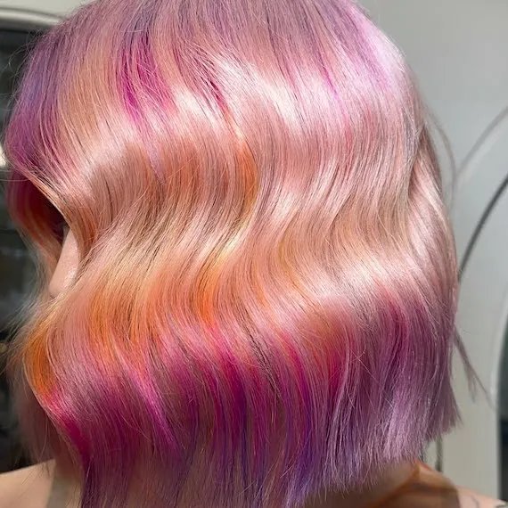 Model with a platinum blonde bob featuring hot pink, orange and violet sections.