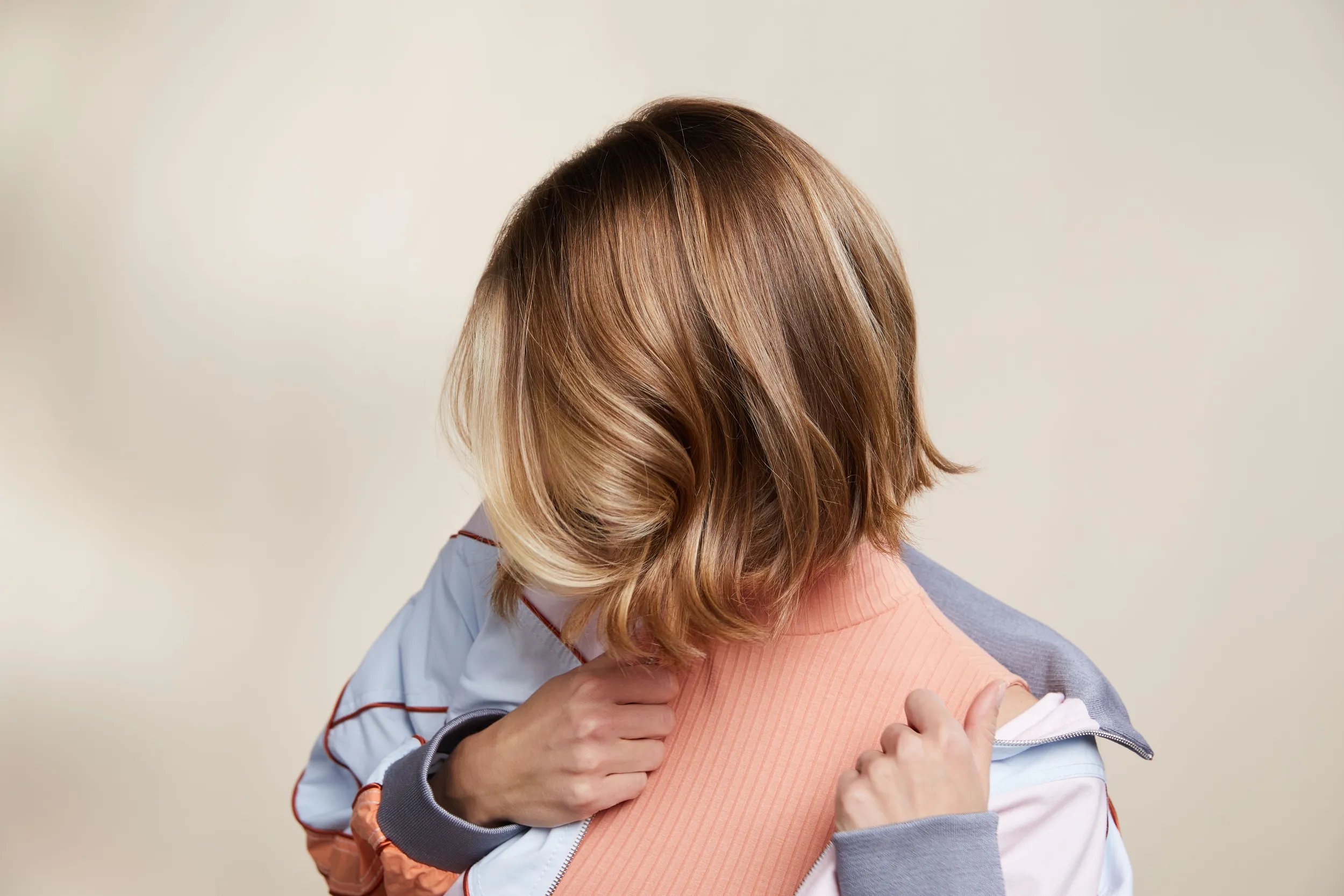 Model with wavy bob hairstyle is seen from behind, with their head slightly tilted. The soft lighting and neutral background highlight the hair’s shine and texture.