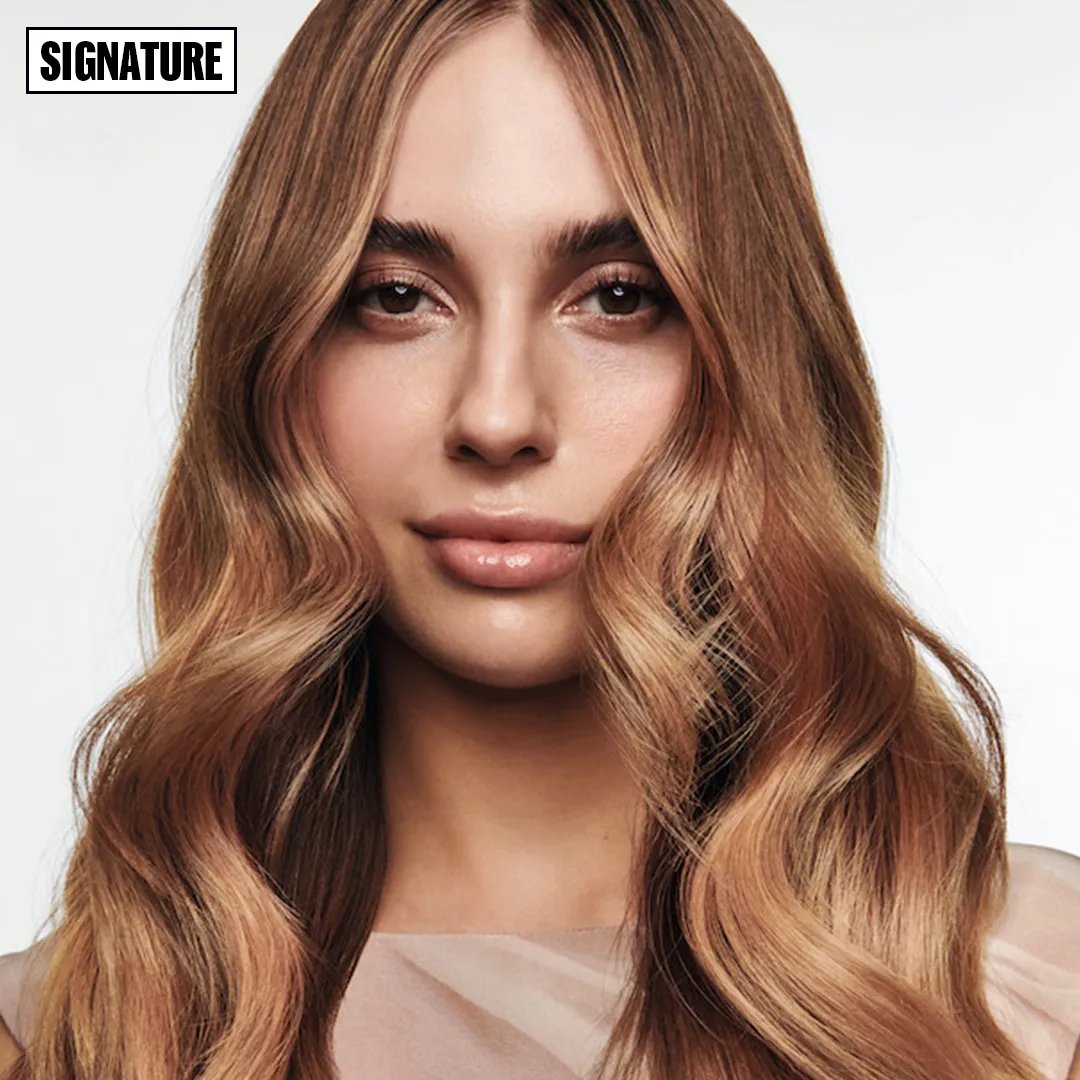 Model facing forward with long and wavy auburn hair.