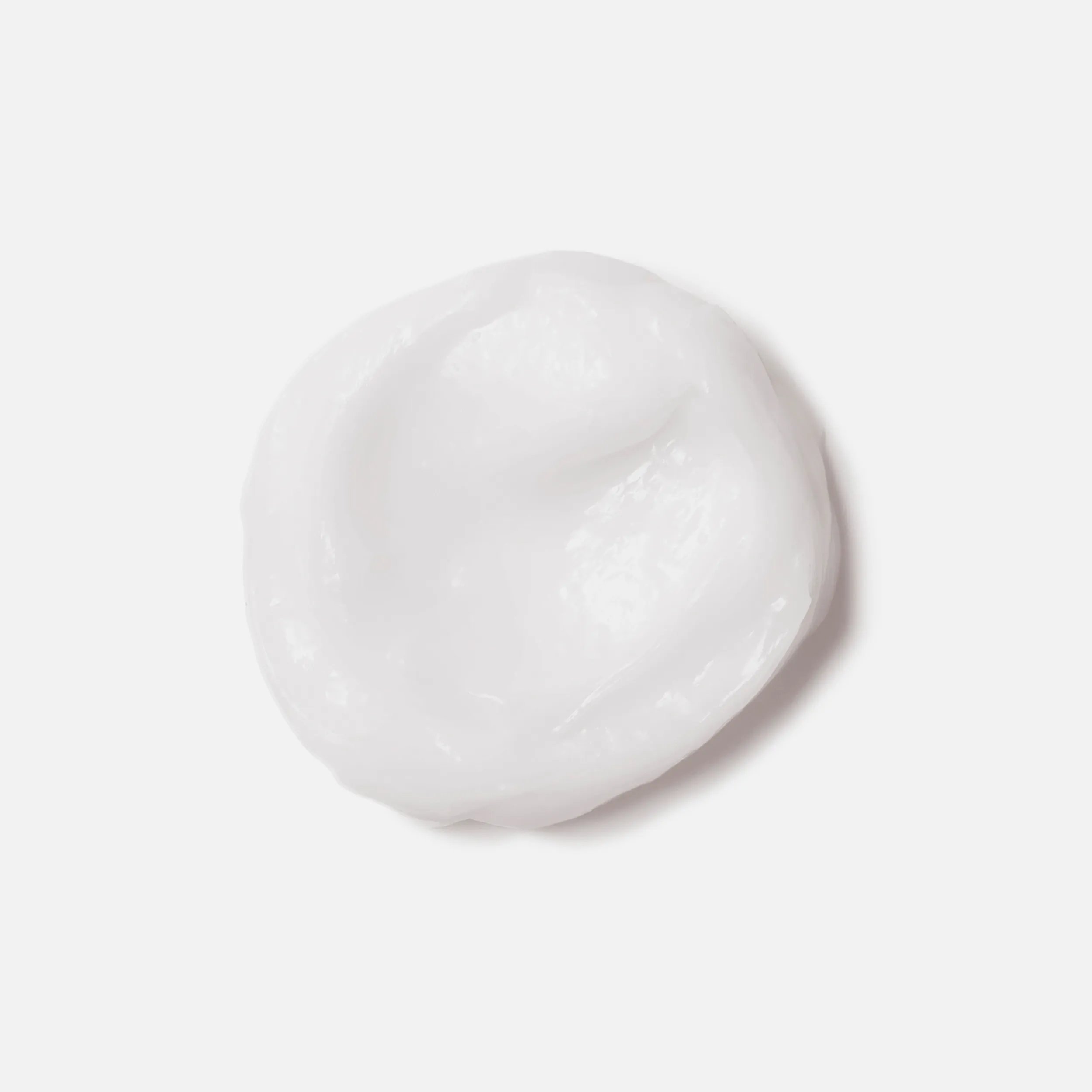 Photographie en gros plan d'une tache circulaire du produit Invigo Brilliance sur un fond blanc, avec un texte indiquant « bouclier antioxydant, aide à contrôler le processus d'oxydation après la coloration" et "purificateur de métaux, protège contre les métaux nocifs dans l'eau ».