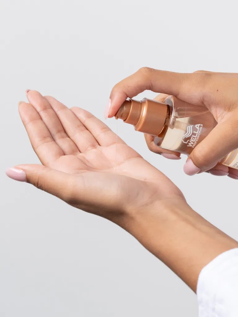 Model pouring ULTIMATE SMOOTH Miracle Oil Serum into palm of hand.