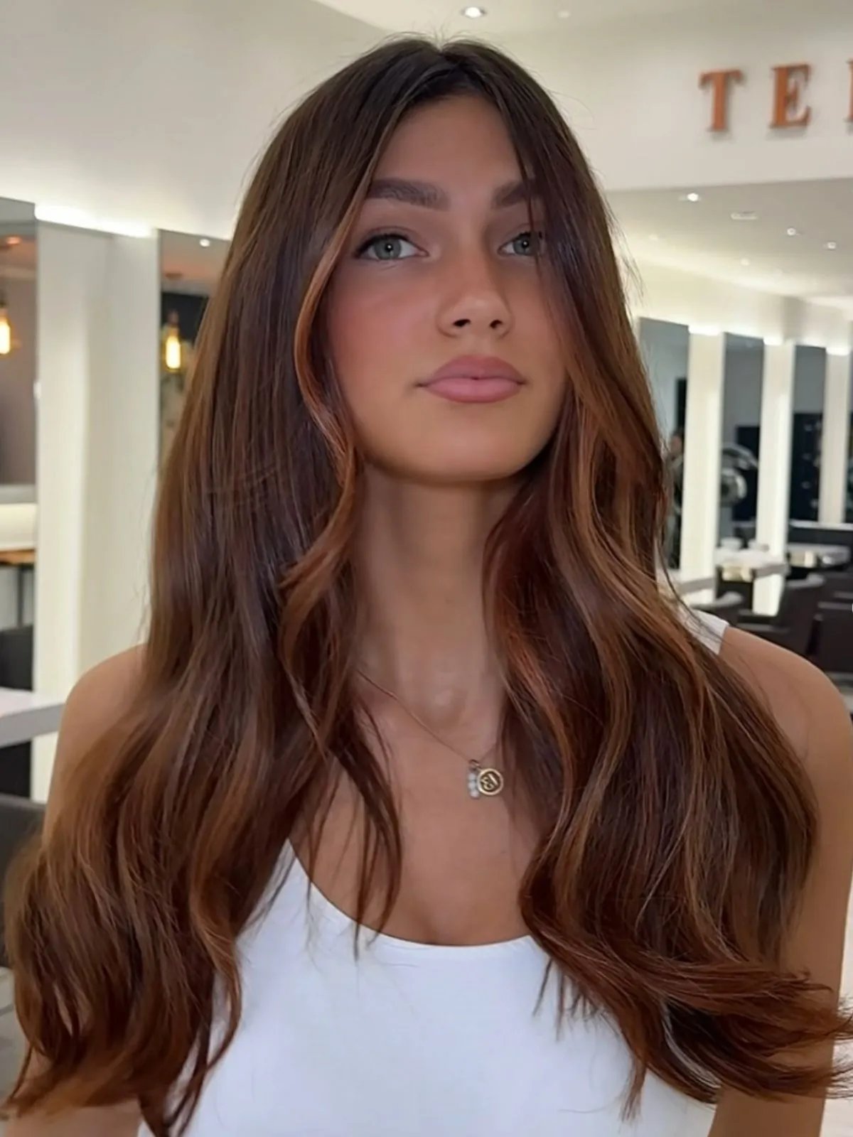 Model with medium brown hair featuring hints of cinnamon red through the mid-lengths and face frame.