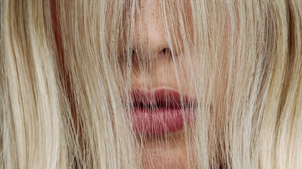 Close-up of model with blonde hair covering their face.