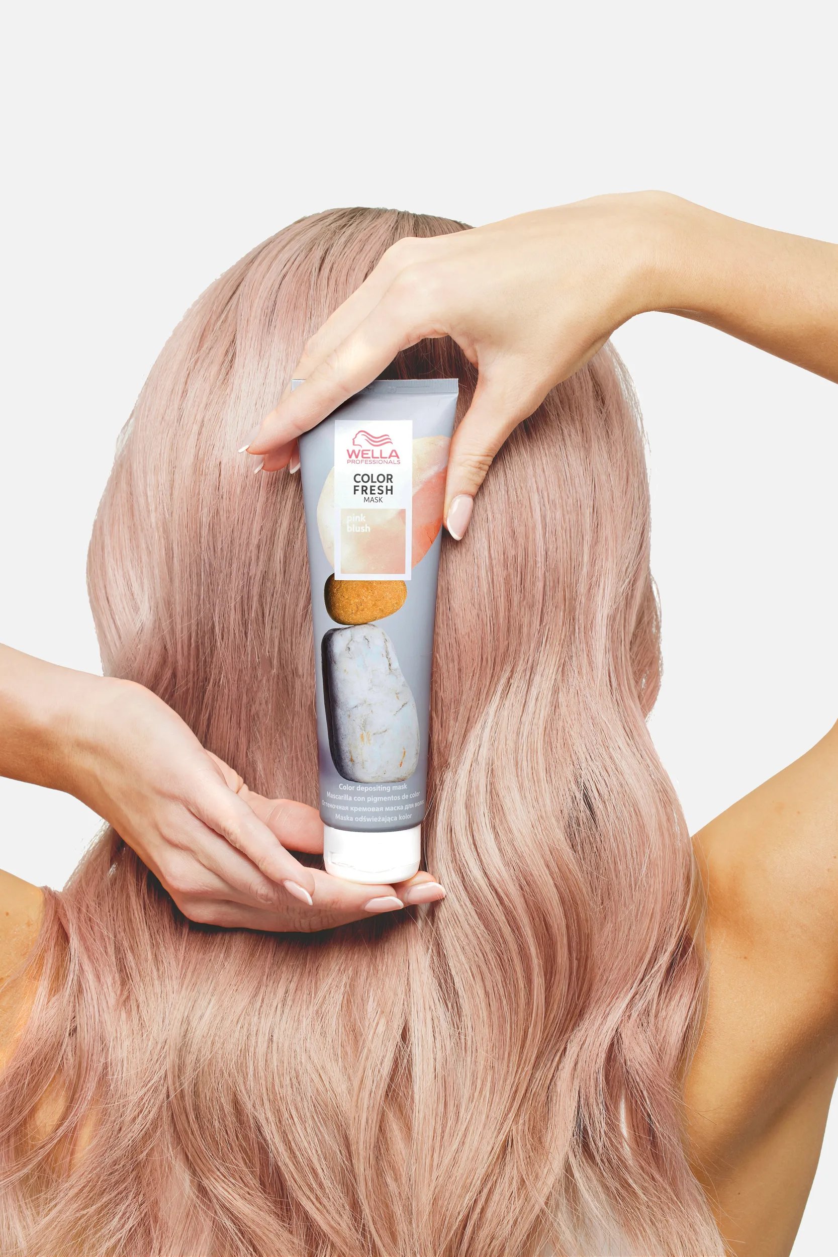 Rückansicht vom Kopf einer Frau, die eine Color Fresh Mask in der Hand hält.