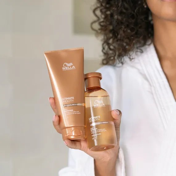 Model holds up ULTIMATE SMOOTH Conditioner and Shampoo. 