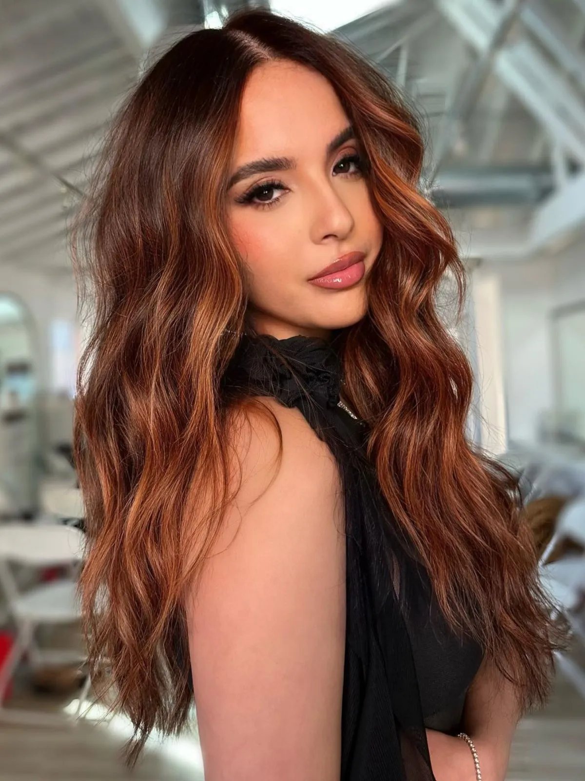 Model with long copper brown hair styled in beachy waves.