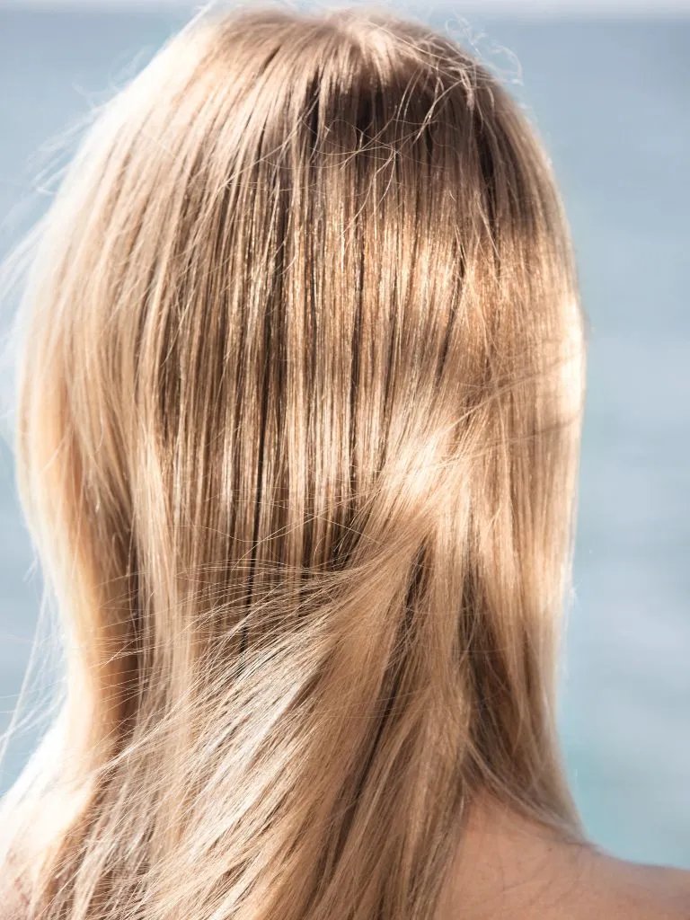 Close-up of a model’s blonde hair with the sun beaming down.