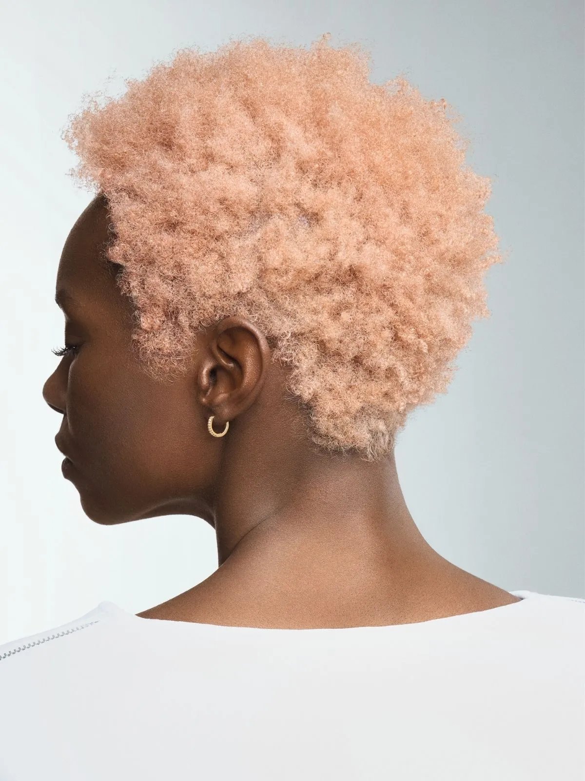 Side profile of model with rose blonde, coily hair.