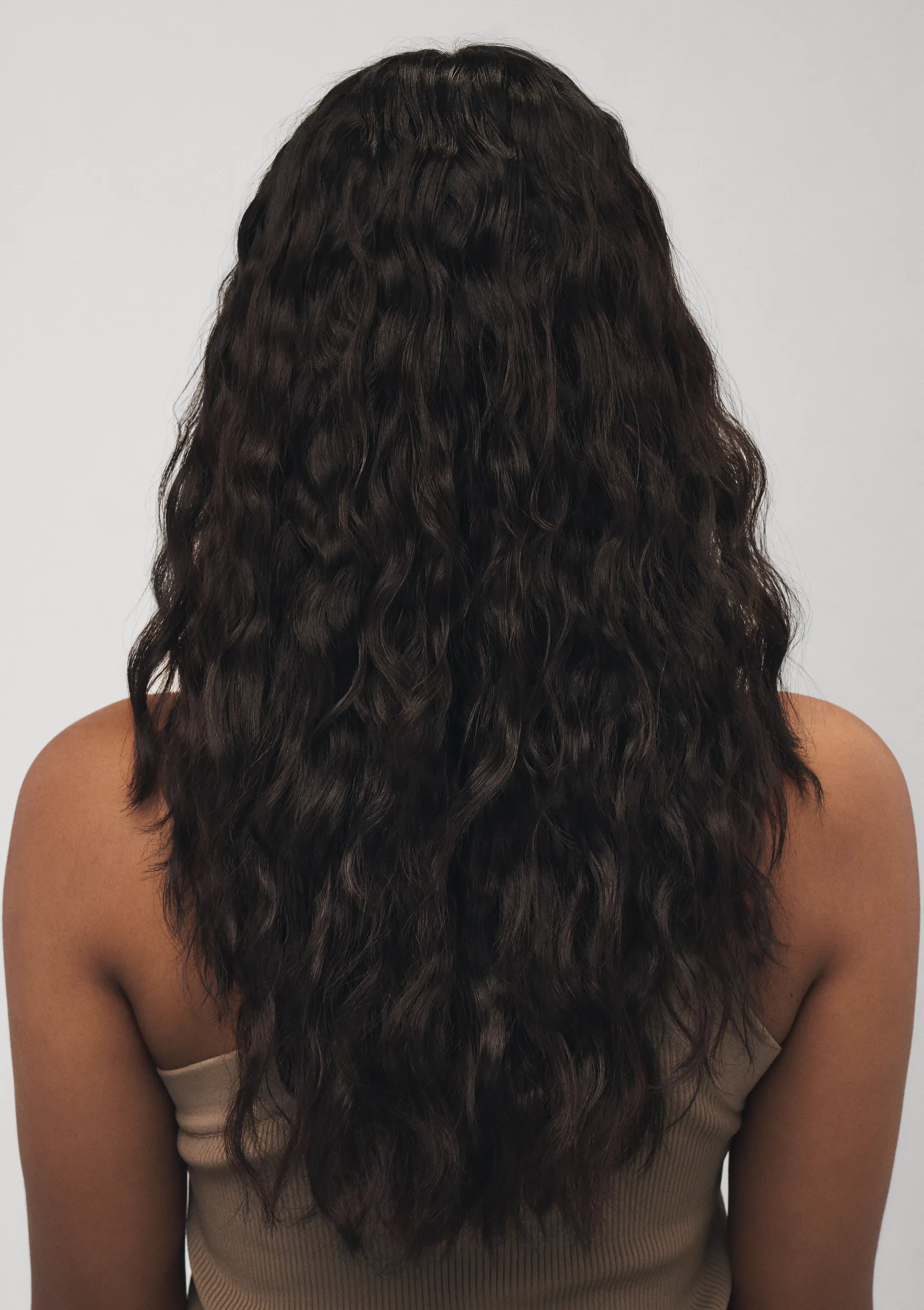 Modelo con cabello largo y castaño de espaldas a la cámara. El cabello luce brillante y con aspecto saludable tras usar los productos Wella Professionals Ultimate Smooth.
