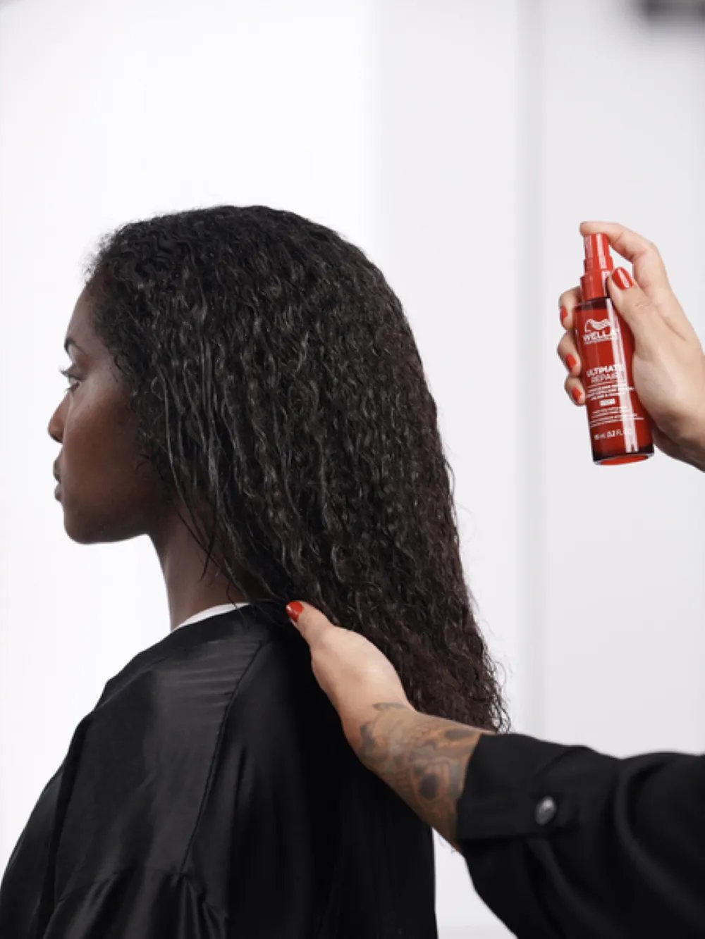 Stylist spraying a hair treatment onto the model’s hair during a salon service
