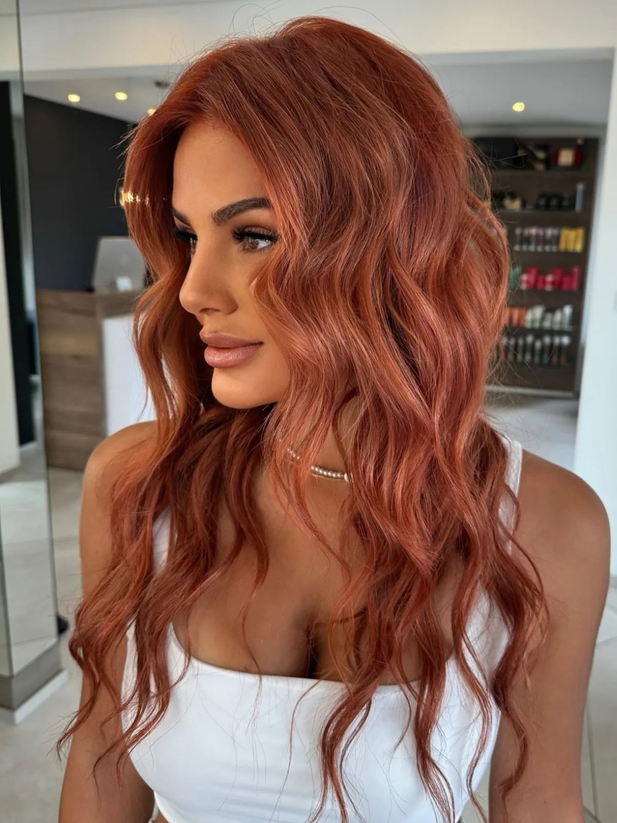 Model’s coral-red, sangria-inspired hair is styled in beachy waves.